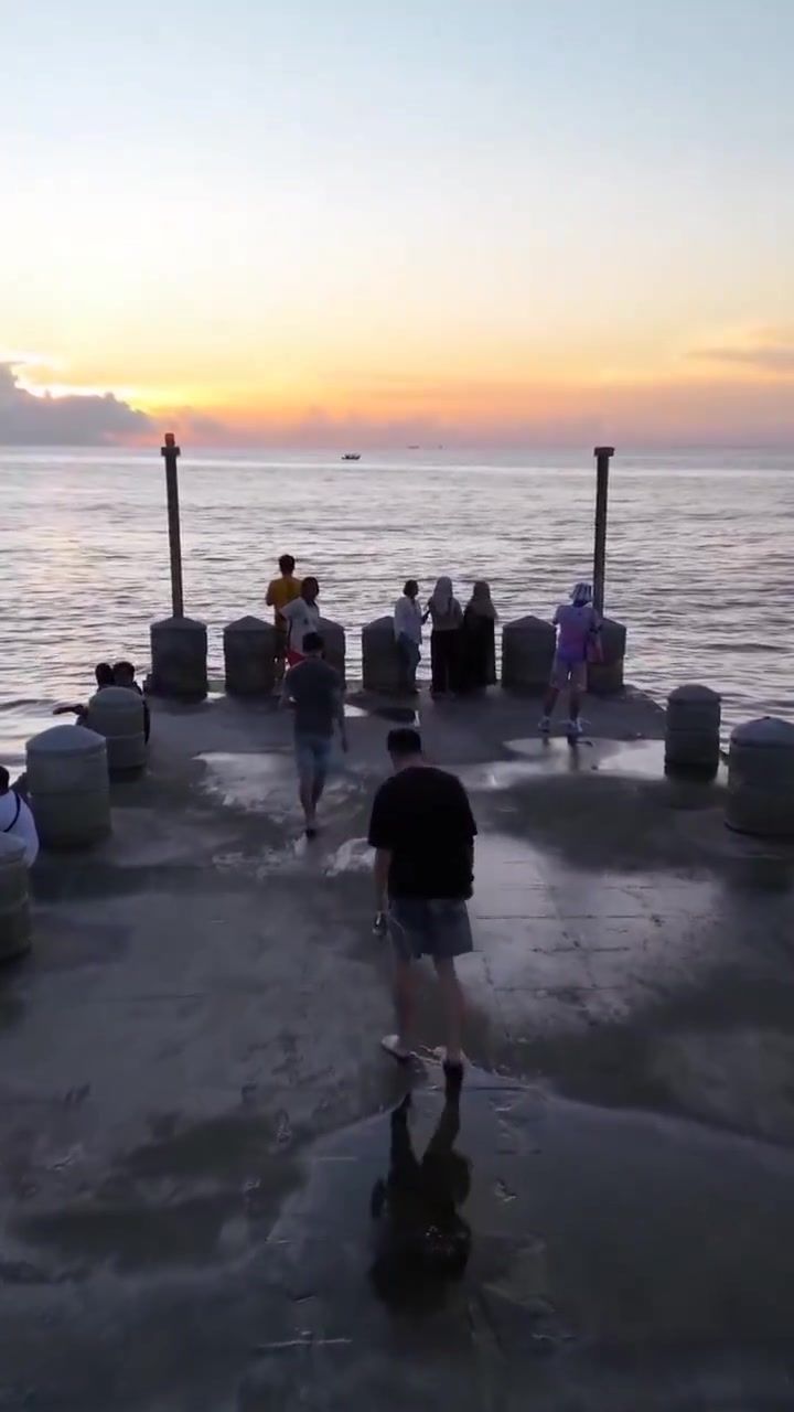 Une vague surprend les promeneurs sur la jetée